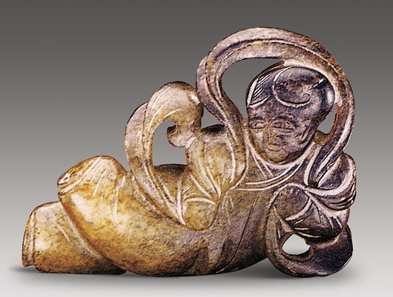 图一 宋 仿唐代飞天童子 长5.2厘米,宽3.8厘米,厚1.3厘米 青玉质,通身有褐色沁。为圆雕,作侧卧状披帛童子。童子大眼直鼻,额顶留发髻。倒八字眉,上身穿交领长衫,下着肥腿裤,双手持飘绕长披帛,一腿直伸,另一腿略翘起,形似飞天。 图一 宋 仿唐代飞天童子 长5.2厘米,宽3.8厘米,厚1.3厘米 青玉质,通身有褐色沁。为圆雕,作侧卧状披帛童子。童子大眼直鼻,额顶留发髻。倒八字眉,上身穿交领长衫,下着肥腿裤,双手持飘绕长披帛,一腿直伸,另一腿略翘起,形似飞天。